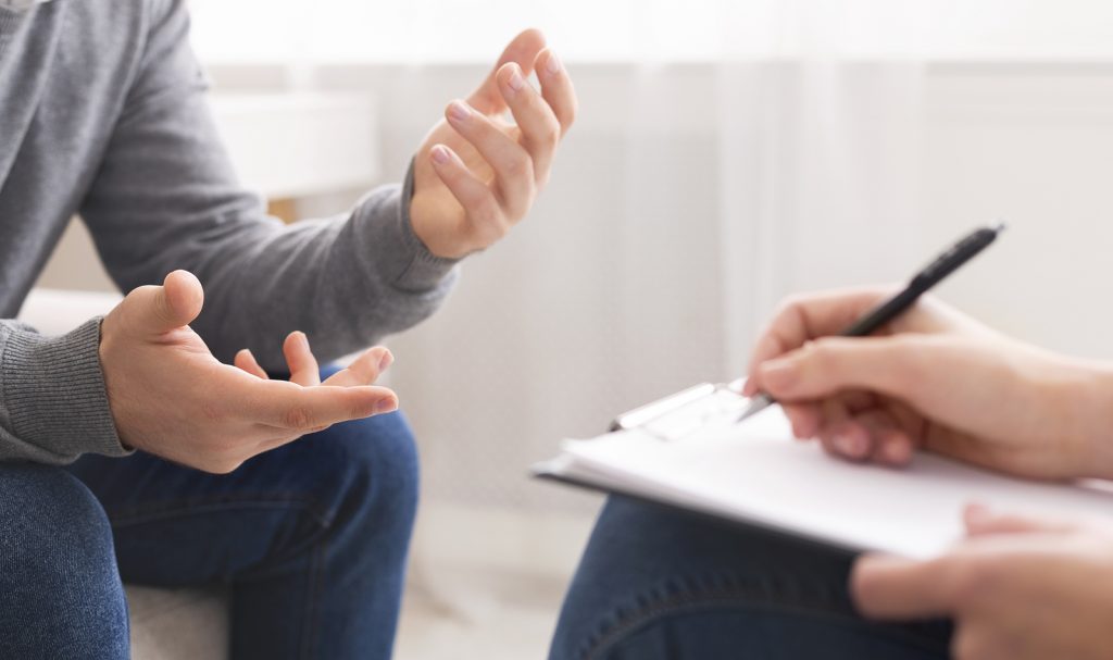 A man sits in a therapy session with his trauma therapist. He is satisfied with his decision to begin online trauma therapy in Texas with online therapist, Addie, from Everyday Bravery.