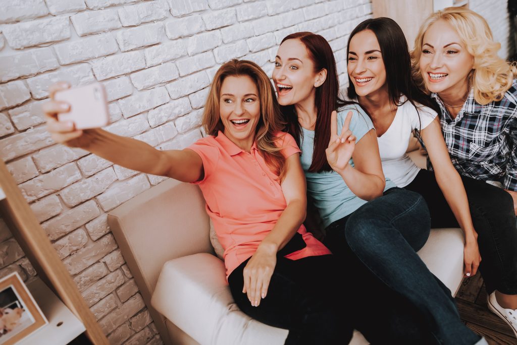 A group of four females are smiling taking a photo together. They are feeling like themselves after starting online trauma therapy in Texas with online counselor, Addie, with Everyday Bravery.